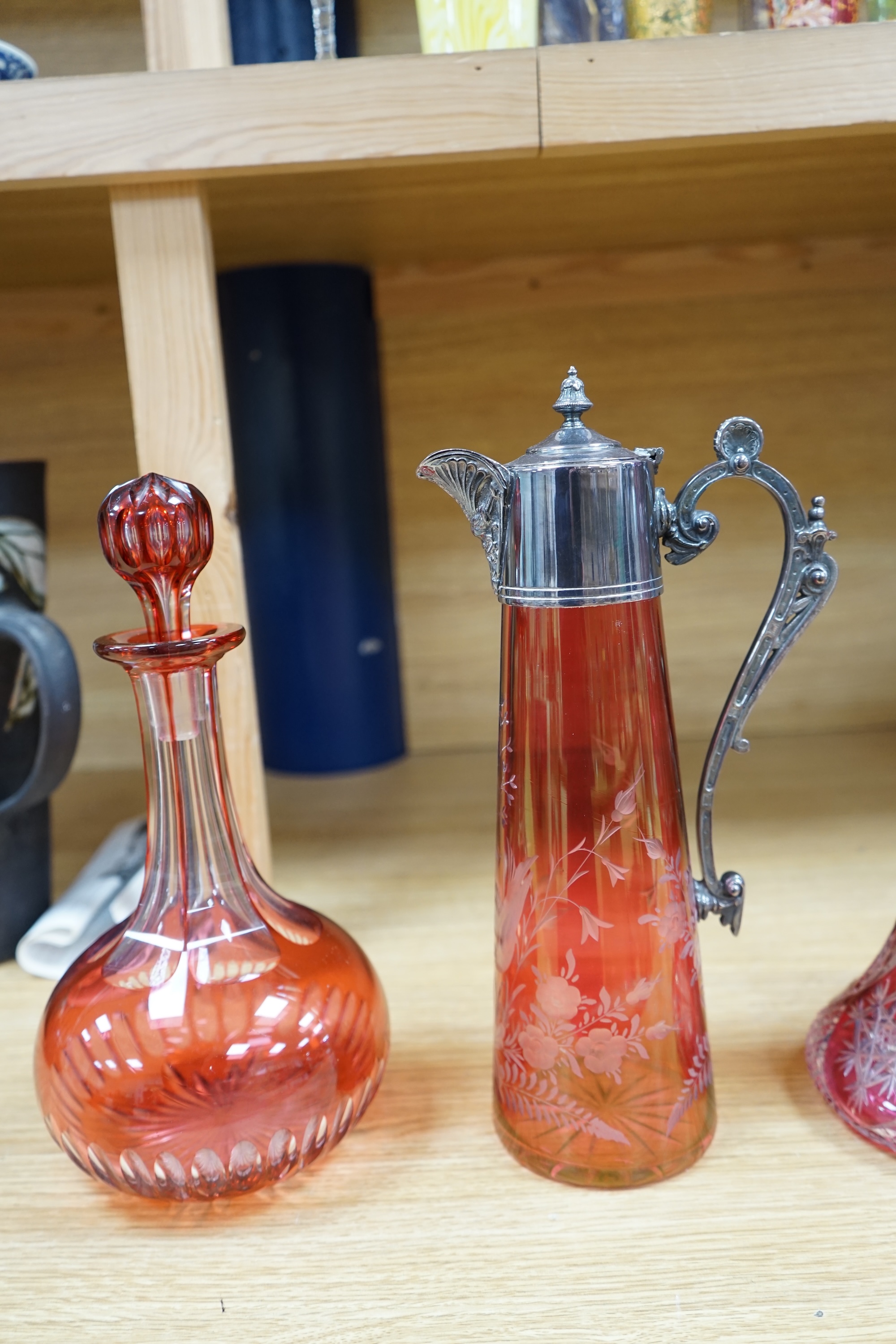 A collection of cranberry glassware comprising three decanters with stoppers and a silver plate mounted ewer, largest 41cm high. Condition - fair to good